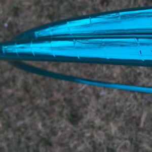 May include: A turquoise metallic hoop with a reflective surface. The hoop is made of a durable material and is designed for use in dance and fitness.