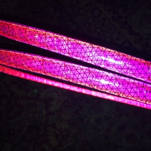 May include: Two pink reflective strips with a diamond pattern. The strips are made of a flexible material and are designed to be seen in low-light conditions.