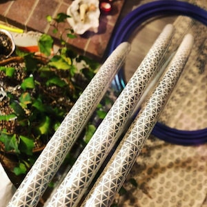 May include: Three silver hoops with a geometric pattern. The hoops are stacked on top of each other and are made of a reflective material.