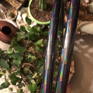 May include: Two iridescent black hula hoops with rainbow reflective tape. The hoops are stacked on top of each other.