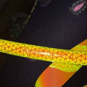 May include: A yellow and orange iridescent hoop with a geometric pattern. The hoop is wrapped around a black fabric with a paisley design.