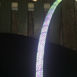 May include: A close-up of a colourful, iridescent hoop with a geometric pattern. The hoop is made of a flexible material and is designed for dance and exercise.