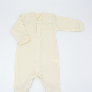 May include: A cream-coloured baby onesie with long sleeves and a button fastening down the front.