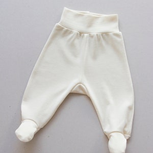 May include: A pair of white baby trousers with fold-over cuffs at the ankles.