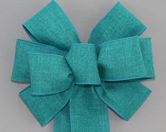 May include: A teal green wired ribbon bow with a textured finish. The bow is tied with a single loop and has a long tail.