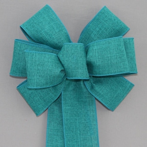 May include: A teal green wired ribbon bow with a textured finish. The bow is tied with a single loop and has a long tail.