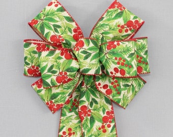 May include: A decorative bow made of fabric featuring a festive pattern of green pine needles and bright red berries on a cream-colored background. The edges of the ribbon are finished with a thin, solid red stitched border throughout the design.