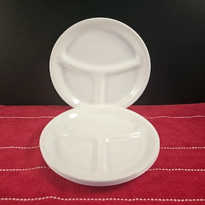 Puede incluir: Un conjunto de cuatro platos blancos divididos. Los platos tienen tres secciones, cada una con un borde redondeado.