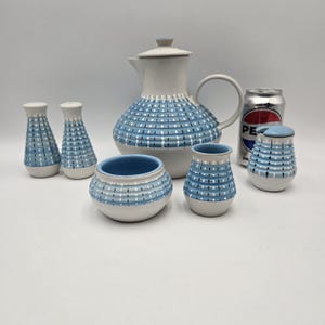 Può includere: Un servizio da tè vintage in ceramica con un motivo a pois blu e bianco. Il set comprende una teiera, zuccheriera, lattiera, saliera e pepiera e un barattolo piccolo. È presente anche una lattina di Pepsi.