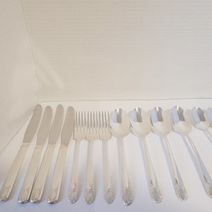 May include: A set of silverware, including knives, forks, and spoons, all with a silver finish. The silverware has a decorative pattern on the handles.
