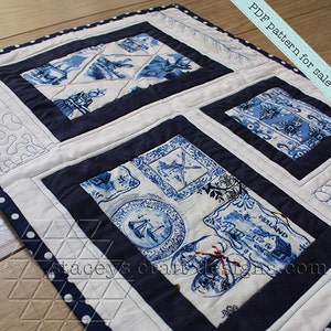 Op de afbeelding: Een wit en blauw patchwork-deken met een donkerblauwe rand en witte stippen. Het deken is gemaakt van vierkanten van verschillende stoffen, elk met een ander ontwerp. Het deken is perfect voor een boerderij of cottage stijl huis.