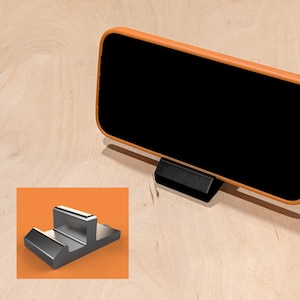 Op de afbeelding: Een witte keramische mok met een zwart handvat en de tekst "But First, Coffee" in een vetgedrukte, zwarte letter. De mok staat op een houten oppervlak. De mok is ongeveer 10 cm hoog.