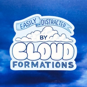 May include: A white sticker with blue text that reads "Easily Distracted by Cloud Formations". The sticker features a cartoon cloud with a banner above it.