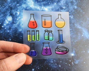 May include: A sheet of clear stickers featuring various science lab equipment, including beakers, flasks, test tubes, and petri dishes. The stickers are filled with colorful liquids and have black outlines.