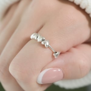 May include: A silver ring with a row of small, heart-shaped charms.