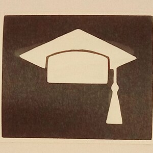 Può includere: Una silhouette bianca di un cappello di laurea con nappa su uno sfondo marrone scuro.