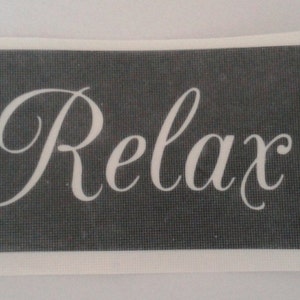 Può includere: Uno stencil bianco su sfondo nero con la parola "Relax" scritta in corsivo.