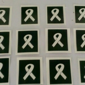 Puede incluir: Doce plantillas de tatuaje temporal blancas con un diseño de cinta blanca sobre fondo negro.
