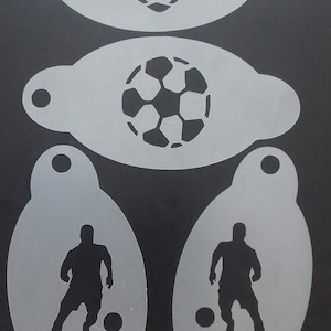 Puede incluir: Un conjunto de plantillas blancas con diseños de fútbol. El conjunto incluye un balón de fútbol en forma de corazón, un balón de fútbol normal y dos siluetas de jugadores. El fondo es negro.