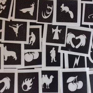 Peut inclure: Une collection de pochoirs noirs et blancs présentant divers motifs, notamment des animaux, des cœurs, des étoiles et un fer à cheval. Les pochoirs sont faits d'un matériau fin et flexible, idéal pour créer des tatouages temporaires ou décorer des objets artisanaux.