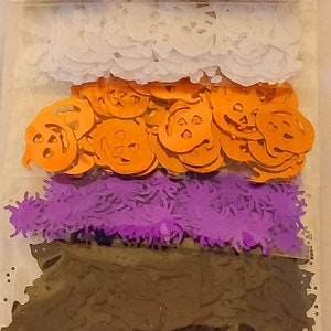 Può includere: Un pacchetto di paillettes di Halloween in varie forme e colori. Le paillettes includono pipistrelli, zucche, ragni e altre forme spettrali. La confezione è etichettata "Halloween Sequins" e include sei confezioni.