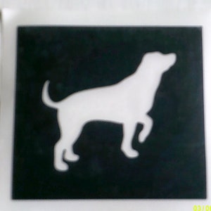 Può includere: Uno stencil in bianco e nero di una silhouette di cane. Il cane è rivolto a destra e ha la coda arrotolata.