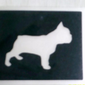 Può includere: Uno stencil in bianco e nero di una silhouette di Bulldog francese. Lo stencil è su uno sfondo nero.