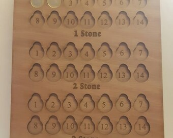 May include: Wooden board with a weight loss tracker. The board has three sections labelled "1 Stone", "2 Stone", and "3 Stone". Each section has 14 slots for coins. The board also has the text "My weight loss journey £1 for lb".