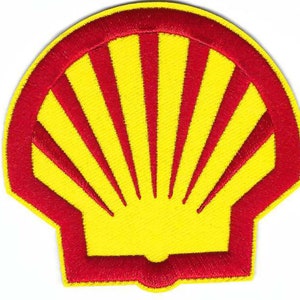 May include: A red and yellow embroidered patch in the shape of a seashell. The seashell has a stylized design with radiating lines.