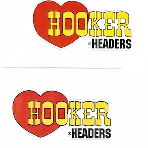 以下が含まれることがあります： 黄色と黒で「HOOKER HEADERS」と書かれた2つのステッカー。 「HOOKER」という単語は赤いハートの形の中にあります。 「HEADERS」という単語は、その下に別の行にあります。