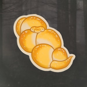 May include: A sticker featuring a stylized illustration of a cluster of golden-yellow mushrooms with white highlights. The sticker has a white border and is set against a dark background.
