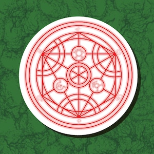 May include: A circular sticker featuring a red alchemic symbol design. The symbol is composed of interconnected circles, lines, and geometric shapes, with a white border. The sticker is set against a green, textured background.