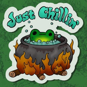 May include: A sticker featuring a cartoon frog relaxing in a bubbling cauldron over a fire. The frog is green with black eyes, and the cauldron is dark gray. The text "Just Chillin'" is above the frog in teal.