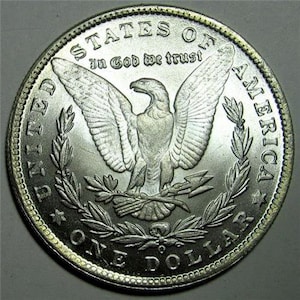 May include: Silver dollar coin with an eagle and the words "United States of America" and "In God We Trust" around the edge.