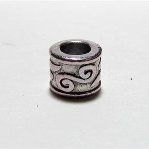 May include: Silver metal bead with a swirling design. The bead has a hole in the center for stringing.