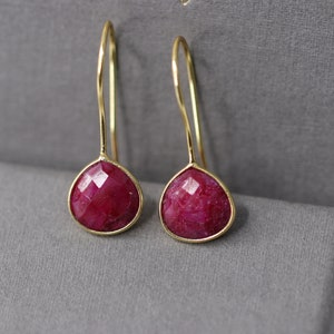 Peut inclure: Une paire de boucles d'oreilles pendantes en or avec des gouttes de pierres précieuses rouges.