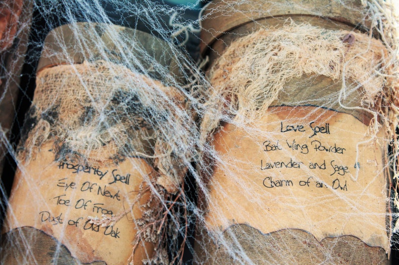 Two jars with handwritten labels and lids covered in cobwebs. The labels read "Prosperity Spell: Eye of Newt, Toe of Frog, Dust of Old Oak" and "Love Spell: Bat Wing Powder, Lavender and Sage, Charm of an Owl". This represents the ebooks that are included in this downloadable pack of rare witchcraft, magical, spell craft, and paganism books.