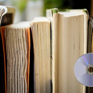 May include: A close-up of a stack of old books with a blank CD on top. The books are all different sizes and have worn covers.