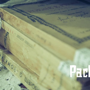 May include: A stack of vintage books wrapped in white lace. The top book has the title "Poesie" and the text "Pack C" is visible in the bottom right corner.