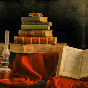 A stack of antique books with leather covers and a worn open book on a red cloth surface. An oil lamp with a glass chimney sits on the left side of the image. These books represent the ebooks that are included in this downloadable pack of rare witchcraft, magical, spell craft, and paganism books.
