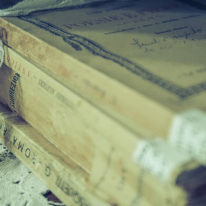 A stack of vintage books with a lace ribbon tied around them. These books represent the ebooks that are included in this downloadable pack of rare witchcraft, magical, spell craft, and paganism books.