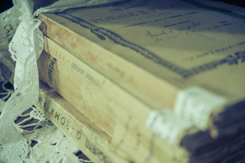 A stack of vintage books with a lace ribbon tied around them. These books represent the ebooks that are included in this downloadable pack of rare witchcraft, magical, spell craft, and paganism books.