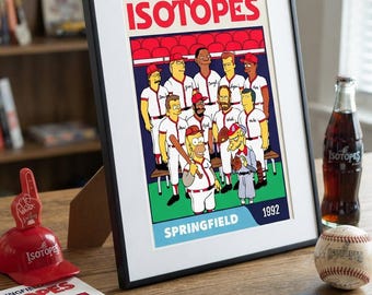 Puede incluir: Un póster enmarcado de un equipo de béisbol de dibujos animados titulado ISOTOPES SPRINGFIELD 1992, con jugadores en uniformes blancos. Junto a él hay un dedo de espuma rojo, una pelota de béisbol, una botella de vidrio y tarjetas coleccionables.