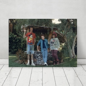 Puede incluir: Tres personas de pie frente a un pozo de piedra. La persona de la izquierda lleva una camisa roja con un gráfico de Mickey Mouse, jeans azules y zapatillas blancas. La persona del medio lleva una camisa azul, jeans azules y zapatillas blancas. La persona de la derecha lleva una camisa blanca con el texto "Class of '84", pantalones rosas y zapatos negros.