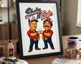 May include: A framed print featuring a caricature of two race car drivers fist-bumping, with the text Shake N Bake above them. The drivers wear red shirts, blue jeans, and hats labeled Wonder and Old Spice. The print is displayed in a black frame.