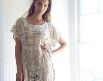May include: A white crochet dress with a delicate floral pattern. The dress has a loose, flowing silhouette and a scoop neckline.