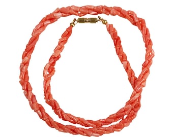May include: A double strand necklace made of coral beads. The beads are a light pink colour and are shaped like small, rectangular sticks. The necklace has a gold clasp.