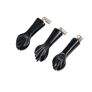May include: Three black carved fist pendants with silver jump rings. The pendants are made of black onyx and are approximately 2 inches long.