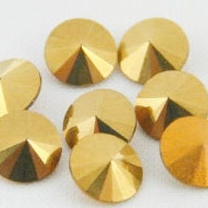 May include: Eight gold-colored, round, flat-backed rhinestones with a pointed, cone-shaped center.