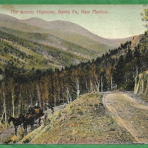 May include: A vintage postcard showing a scenic highway in Santa Fe, New Mexico. The road winds through a lush forest with a mountain range in the background. The text "The Scenic Highway, Santa Fe, New Mexico." is printed at the top of the postcard.